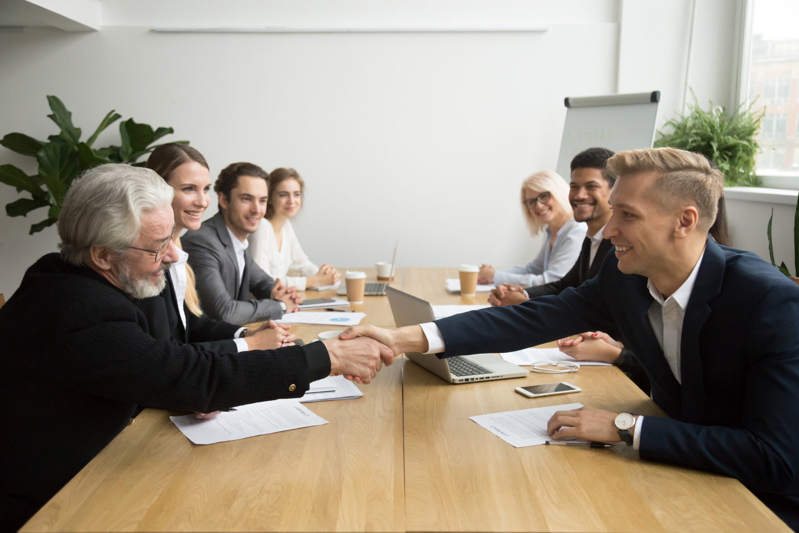 Senior investor buying startup handshaking young entrepreneur at client